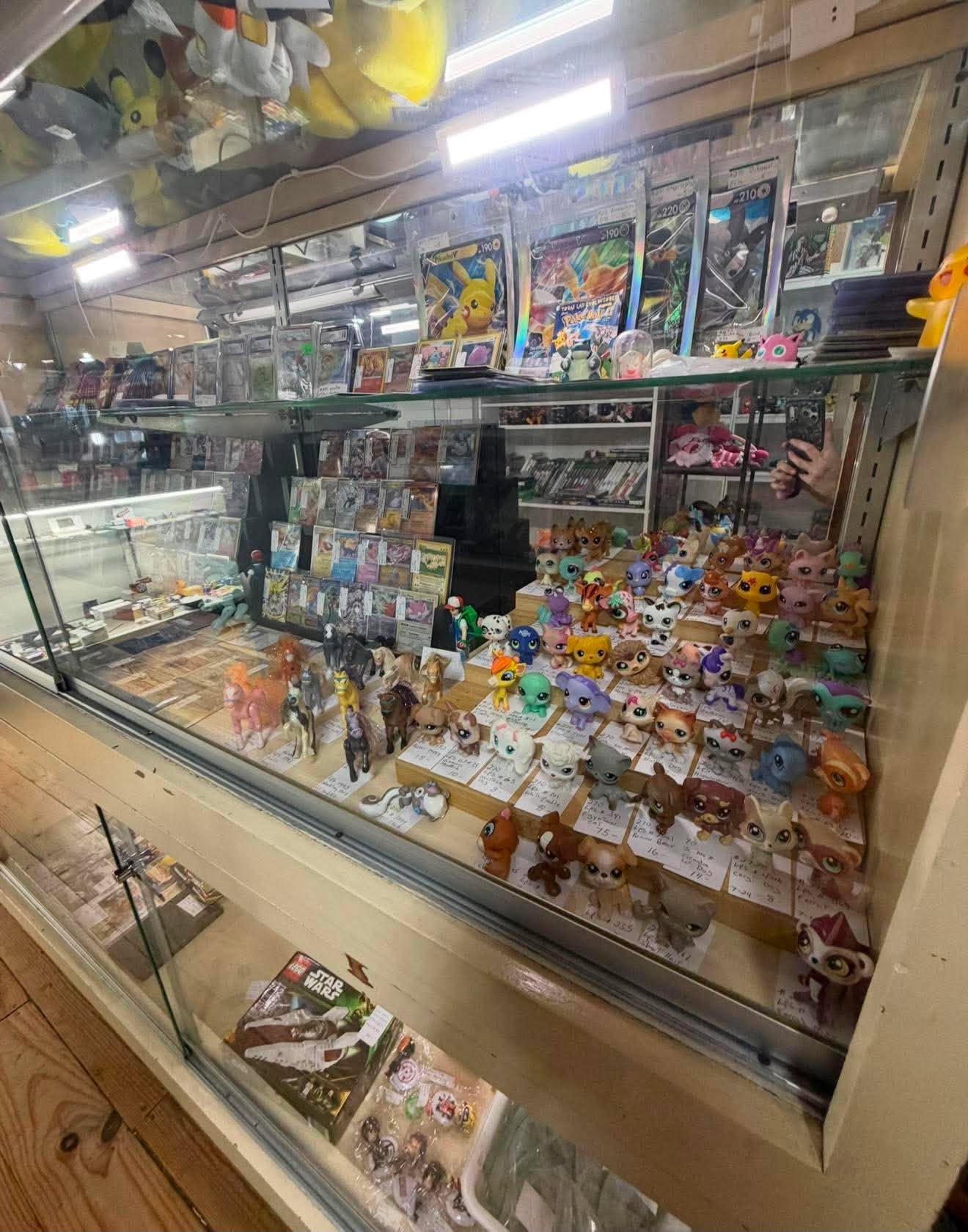 A glass case filled with trading cards, toys and colorful collectibles