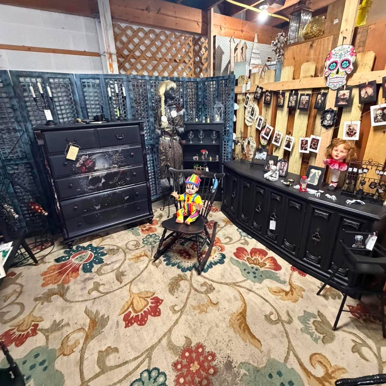 A dramatic vendor booth with dark painted furniture, dolls and unusual art