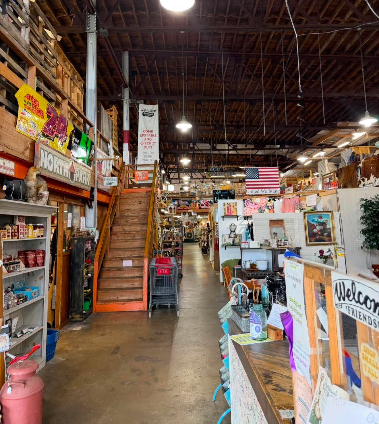The spacious main aisle, wooden staircase and booths inside The Vintage Warehouse